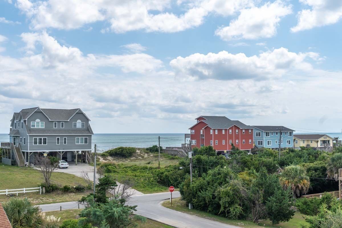 A coastal residential area with houses, a stop sign, and a view of the ocean.