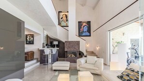 A spacious living area with a glass coffee table, white sofas, and a fireplace. - DIANE By Terry's Homes (Cannes)