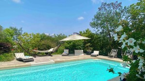 A rectangular swimming pool with clear blue water, surrounded by lounge chairs and a hammock. - DIANE By Terry's Homes (Cannes)