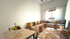 Ein Wohnzimmer mit einem Holzesstisch, einer Couch mit Kissen, einem gemusterten Teppich und einem Fernseher auf einem Holzboden.