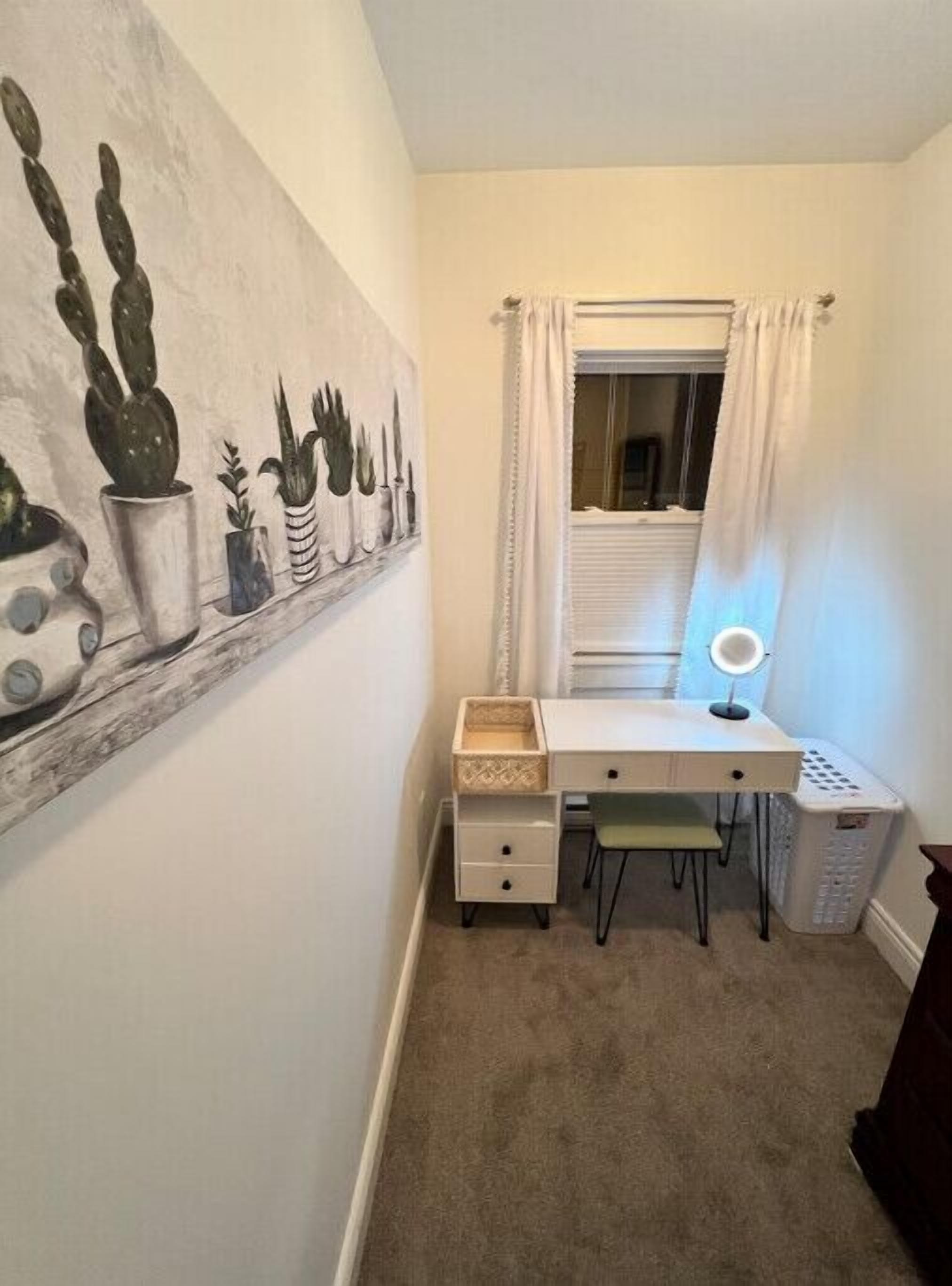 Una habitación pequeña y ordenada, con escritorio, silla y estante con plantas en macetas.