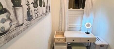 Una habitación pequeña y ordenada, con escritorio, silla y estante con plantas en macetas.
