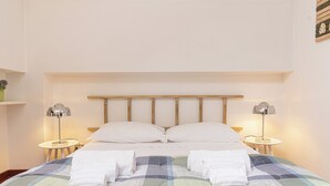 A neatly made bed with a checkered bedspread, two bedside lamps, and a wooden headboard.