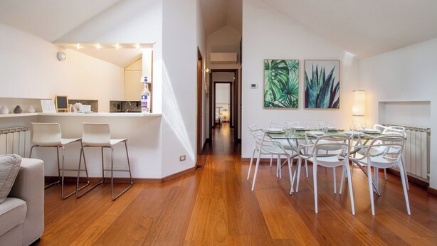 A modern kitchen with a dining area, wooden floors, and a skylight.