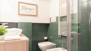 A bathroom with a shower, bidet, and sink.