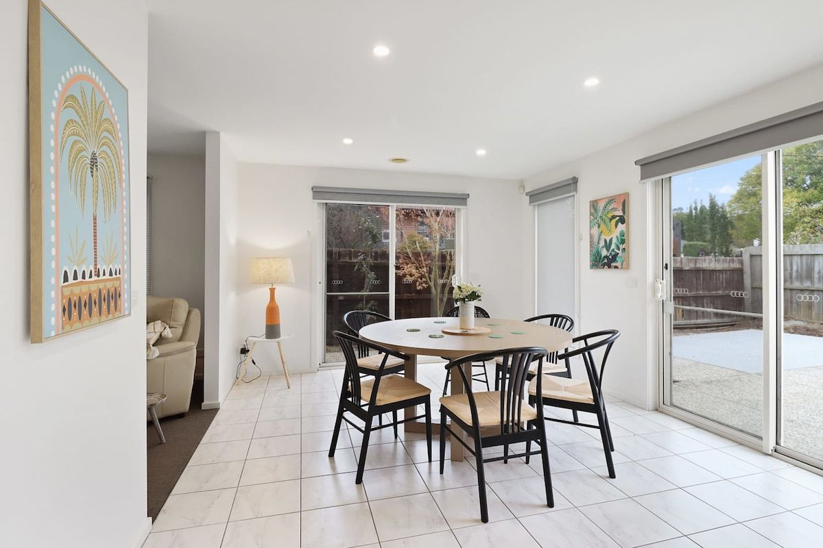 A dining area with a round table and chairs, a sofa, and a lamp.