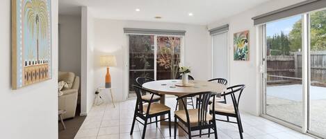 A dining area with a round table and chairs, a sofa, and a lamp.