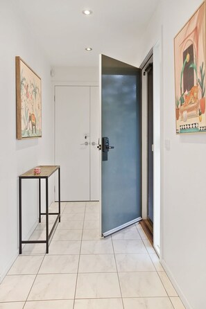 A hallway with a closed door, a small table, and two wall-mounted artworks.