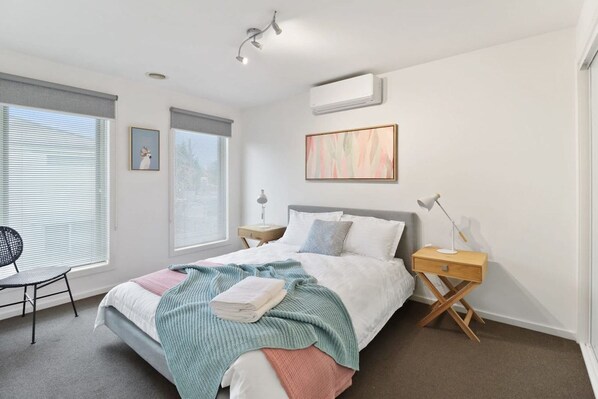 A modern bedroom with a bed, bedside tables, a chair, and artwork on the walls.