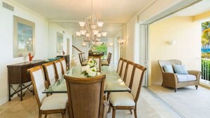 A spacious dining area with a long table, chairs, and a chandelier. - Villa Renaissance 2 Story, 4 Bedrooms, 4 1/2 Baths, Ocean Front Master Bedroom (Grace Bay)