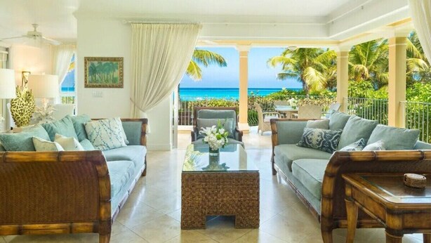 A spacious living room with two sofas, a coffee table, and a view of the ocean. - Villa Renaissance 2 Story, 4 Bedrooms, 4 1/2 Baths, Ocean Front Master Bedroom (Grace Bay)