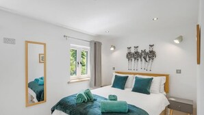 A bedroom with a bed, a mirror, a window, and wall art. - Modern Home in Bude, Private Parking & Garden (Bude)