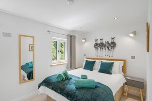 A bedroom with a bed, a mirror, a window, and wall art. - Modern Home in Bude, Private Parking & Garden (Bude)