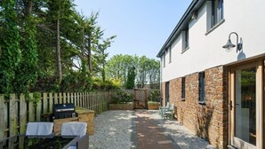 A patio with outdoor furniture, a barbecue grill, and a stone wall. - Modern Home in Bude, Private Parking & Garden (Bude)
