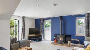 A living room with a fireplace, a television, and a sofa. - Modern Home in Bude, Private Parking & Garden (Bude)