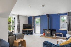 A living room with a fireplace, a television, and a sofa. - Modern Home in Bude, Private Parking & Garden (Bude)