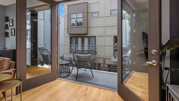 Apartamento moderno com varanda, mobiliado com mesa e cadeiras, e vista para edifícios vizinhos.