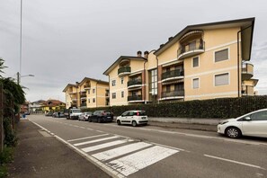 Een woonstraat met meerlaags appartementencomplexen, een zebrapad en geparkeerde auto's.