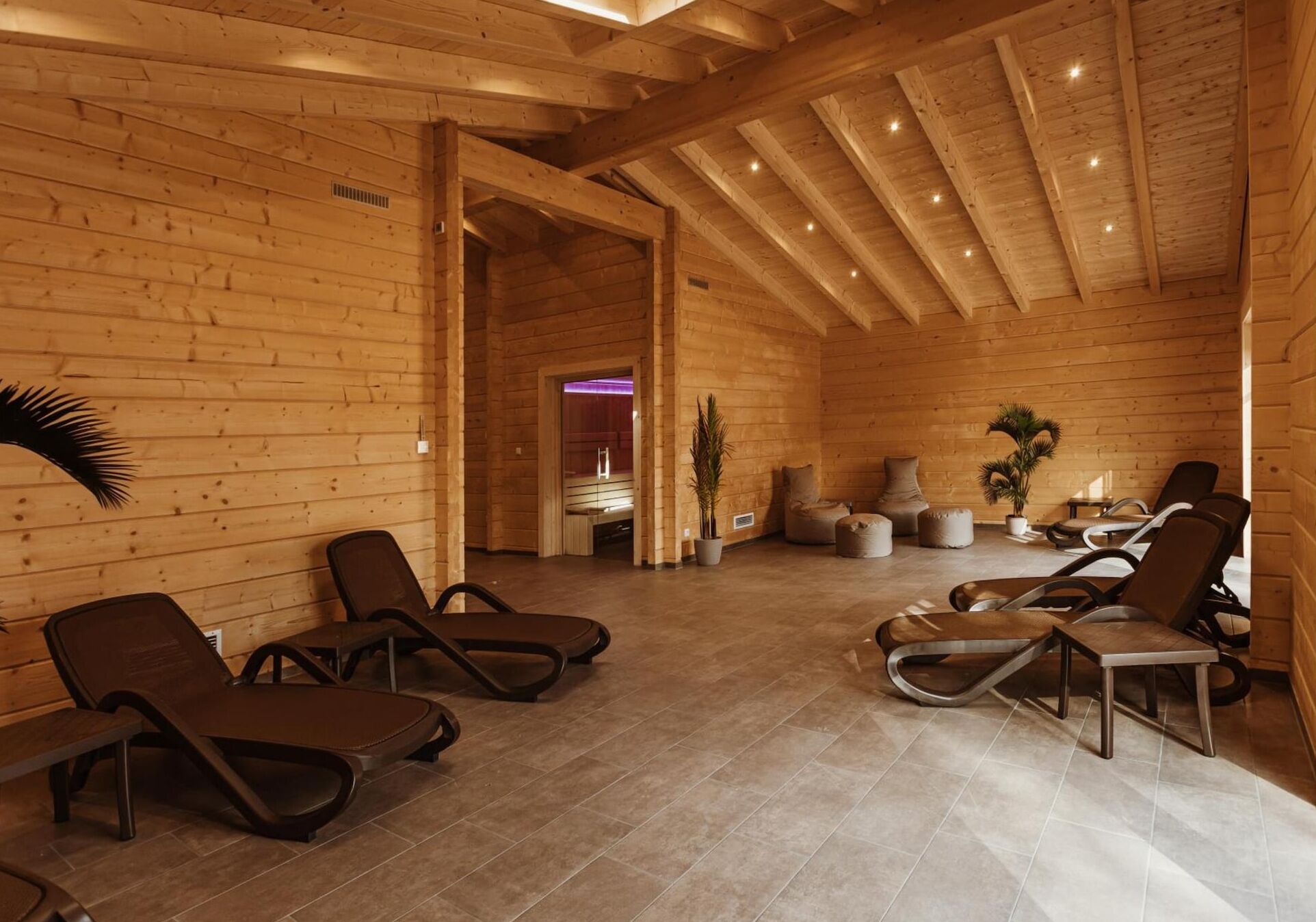 A wooden interior with lounge chairs and a massage table, suggesting a spa or relaxation area.