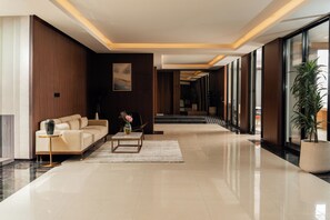 A modern hotel lobby with a sofa, coffee table, and potted plants.