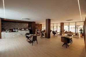 A modern hotel lobby with a marble reception desk, dining area with tables and chairs, large windows, and a wooden floor. - Howard Johnson by Wyndham Riyadh Al Nasiriyah (Riyadh)