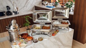 Montaje de bufé con varios recipientes de comida y salsas.