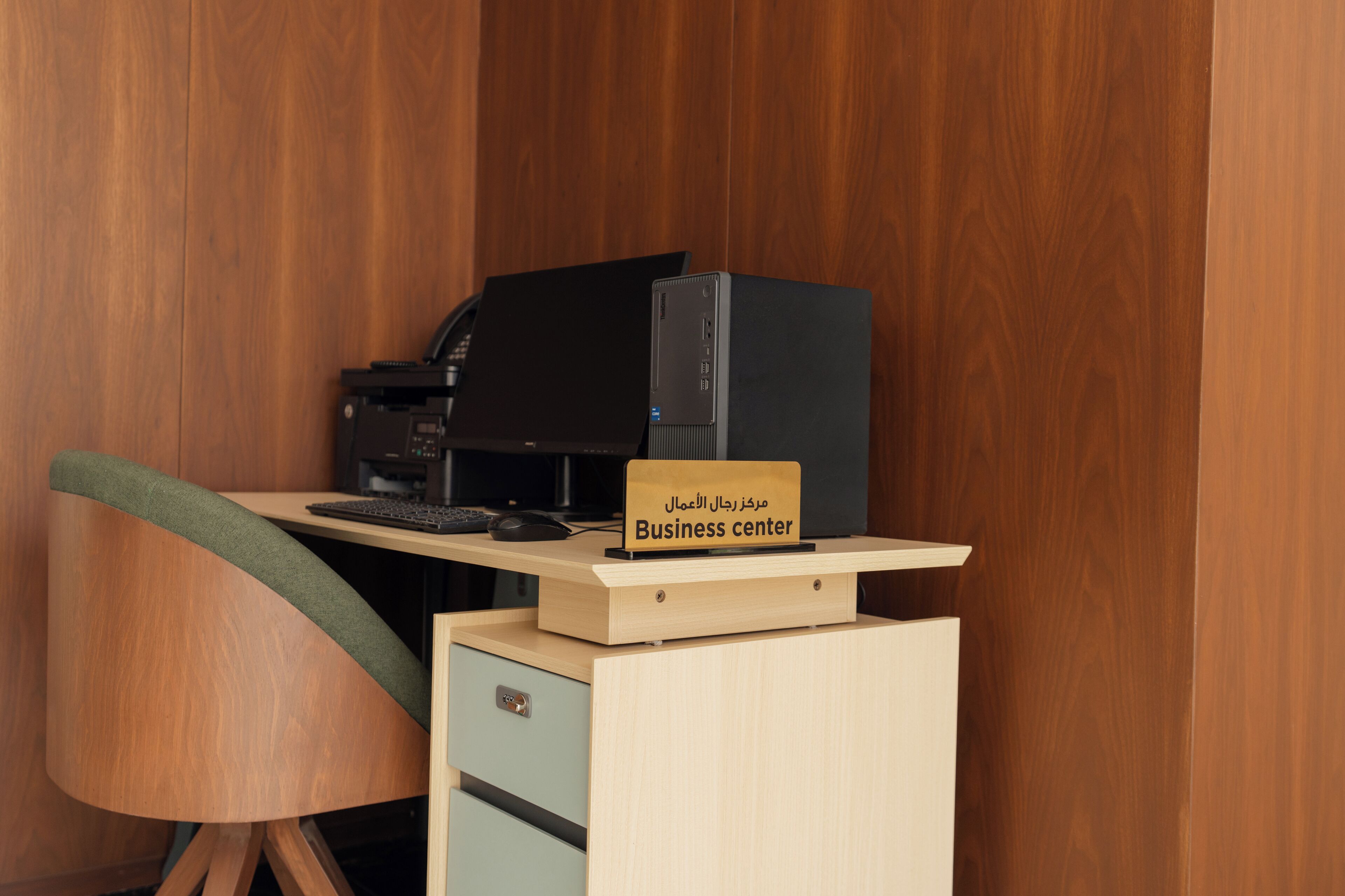 Een kleine kantoorruimte met een bureau, een computer en een bord waarop een business center wordt aangegeven.