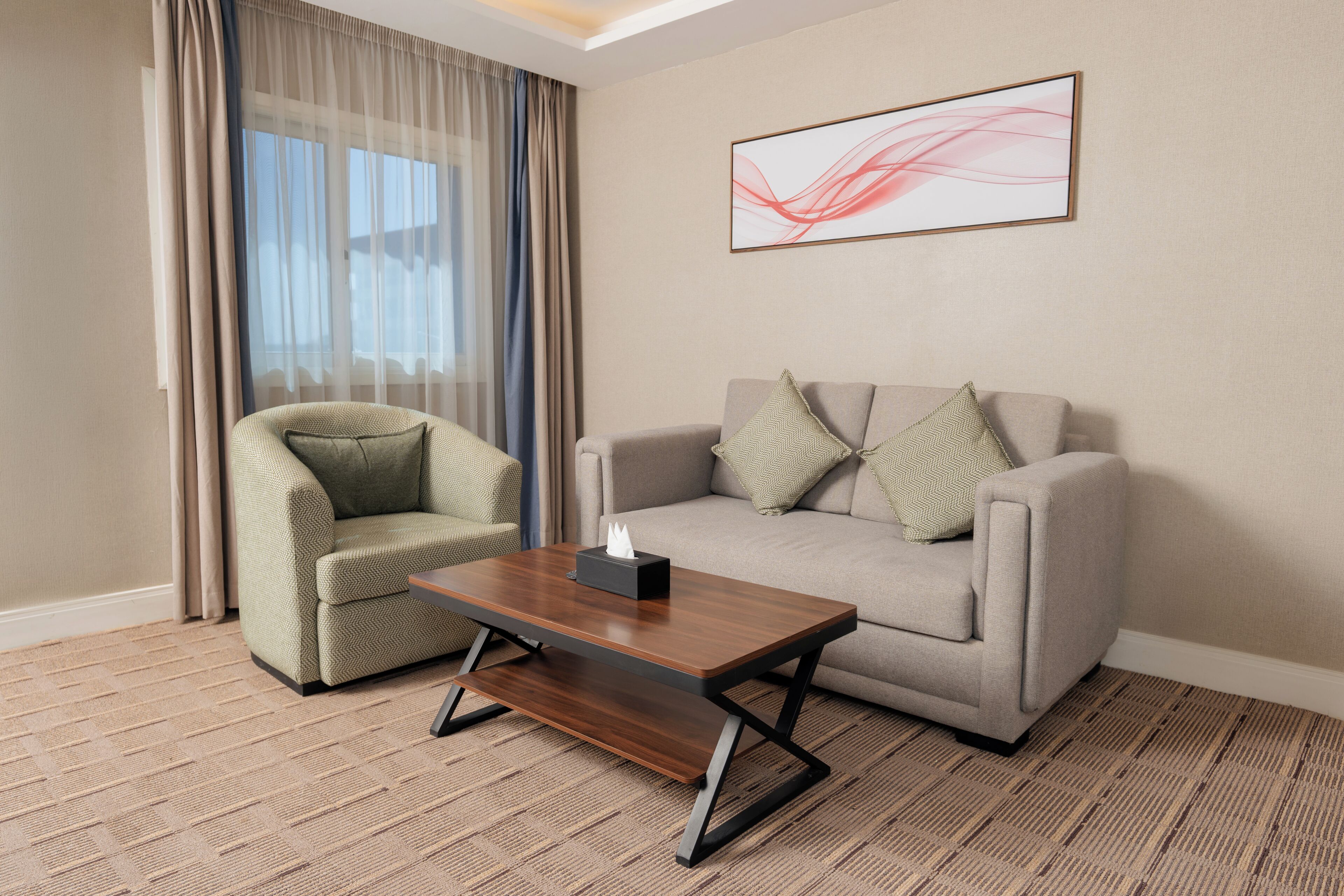 Une chambre d’hôtel avec un canapé, un fauteuil et une table basse.