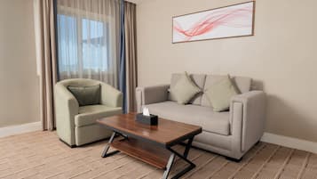 Une chambre d’hôtel avec un canapé, un fauteuil et une table basse.