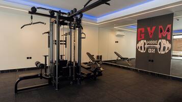 Un gimnasio con equipo de ejercicio, una banca y una pared con la inscripción 'GYM'.