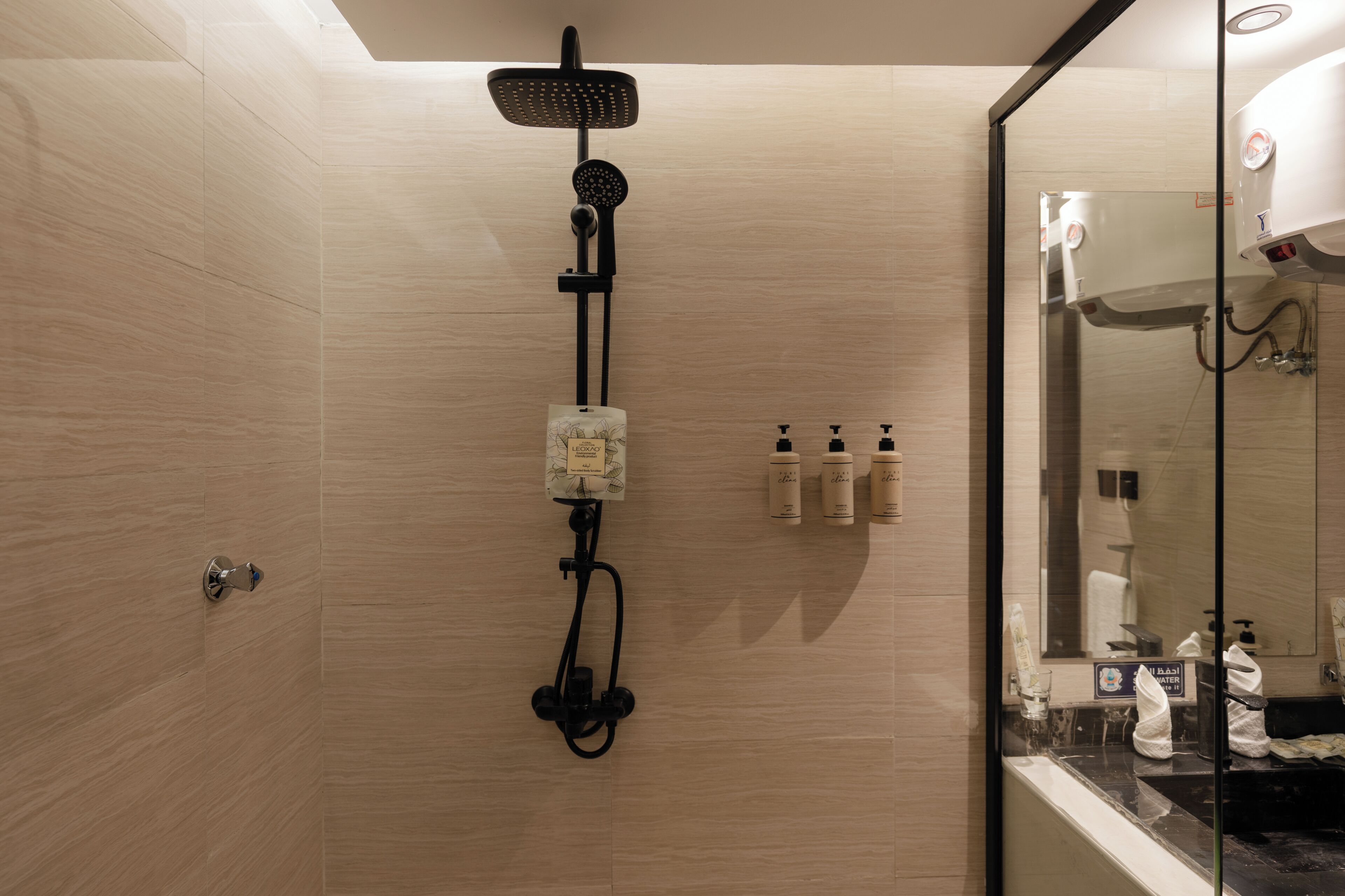 A modern bathroom with a shower, a glass-enclosed vanity, and toiletries.