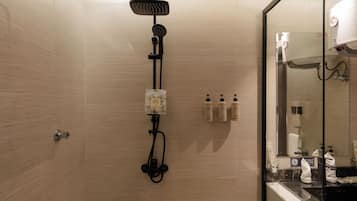 A modern bathroom with a shower, a glass-enclosed vanity, and toiletries.