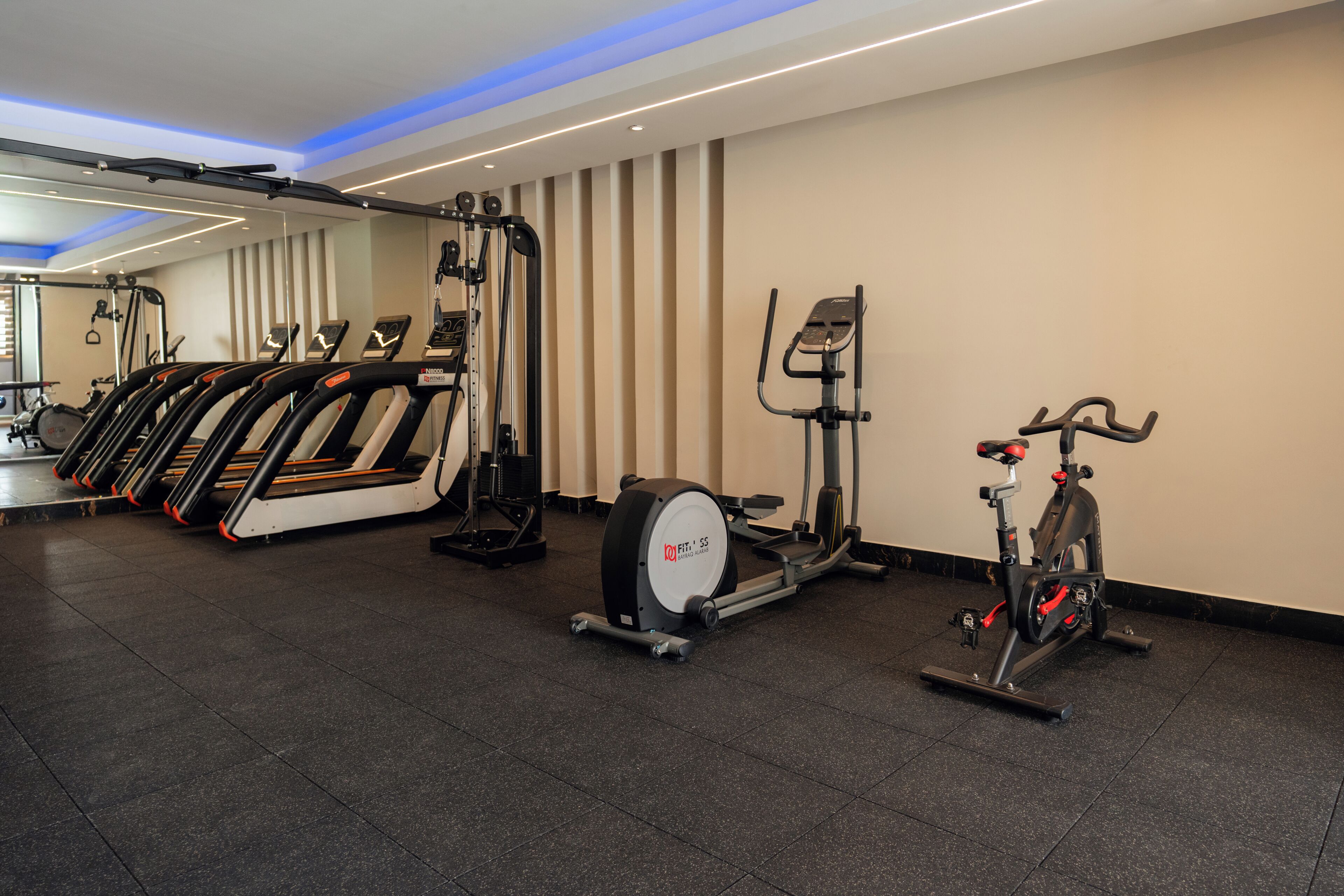 Un gimnasio con cintas de correr, elíptica y bicicleta estática.