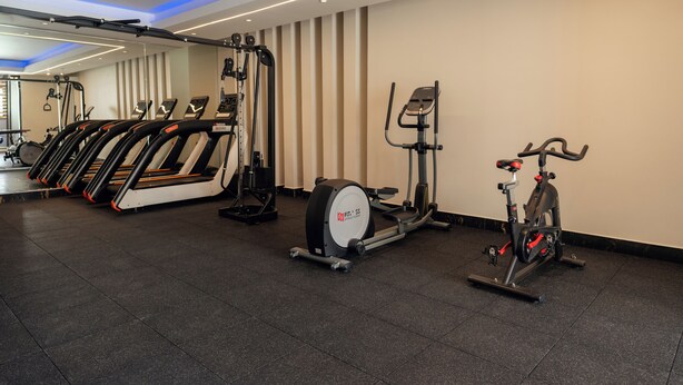 Un gimnasio con cintas de correr, elíptica y bicicleta estática.