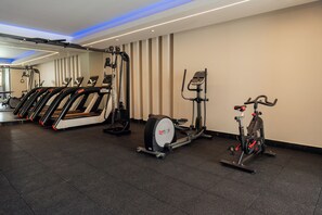 Un gimnasio con cintas de correr, elíptica y bicicleta estática.
