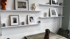 A dining area with a table and chairs, white shelving with framed pictures and small decorative items, and a statue on the wall. - 2 bedroom apartment  (London)