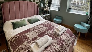 A modern bedroom with a large bed, a dresser, a vanity, and a window with a view. - 2 bedroom apartment  (London)