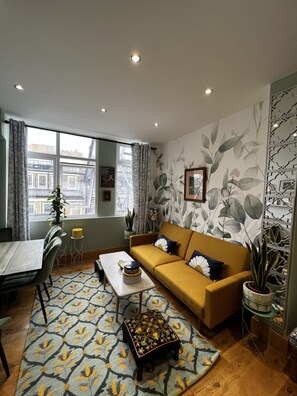 Een woonkamer met een bank, een salontafel, een kamerkleed en een eethoek met stoelen en een tafel.