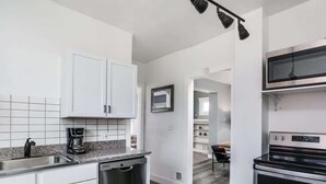 Eine moderne Küche mit weißen Schränken, einem Geschirrspüler, einer Kaffeemaschine und einem Backofen.