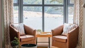 A room with two leather armchairs facing a large window overlooking a beach. - Blackstone -  stylish apartment with incredible views looking out over the Salcombe estuary (Salcombe)
