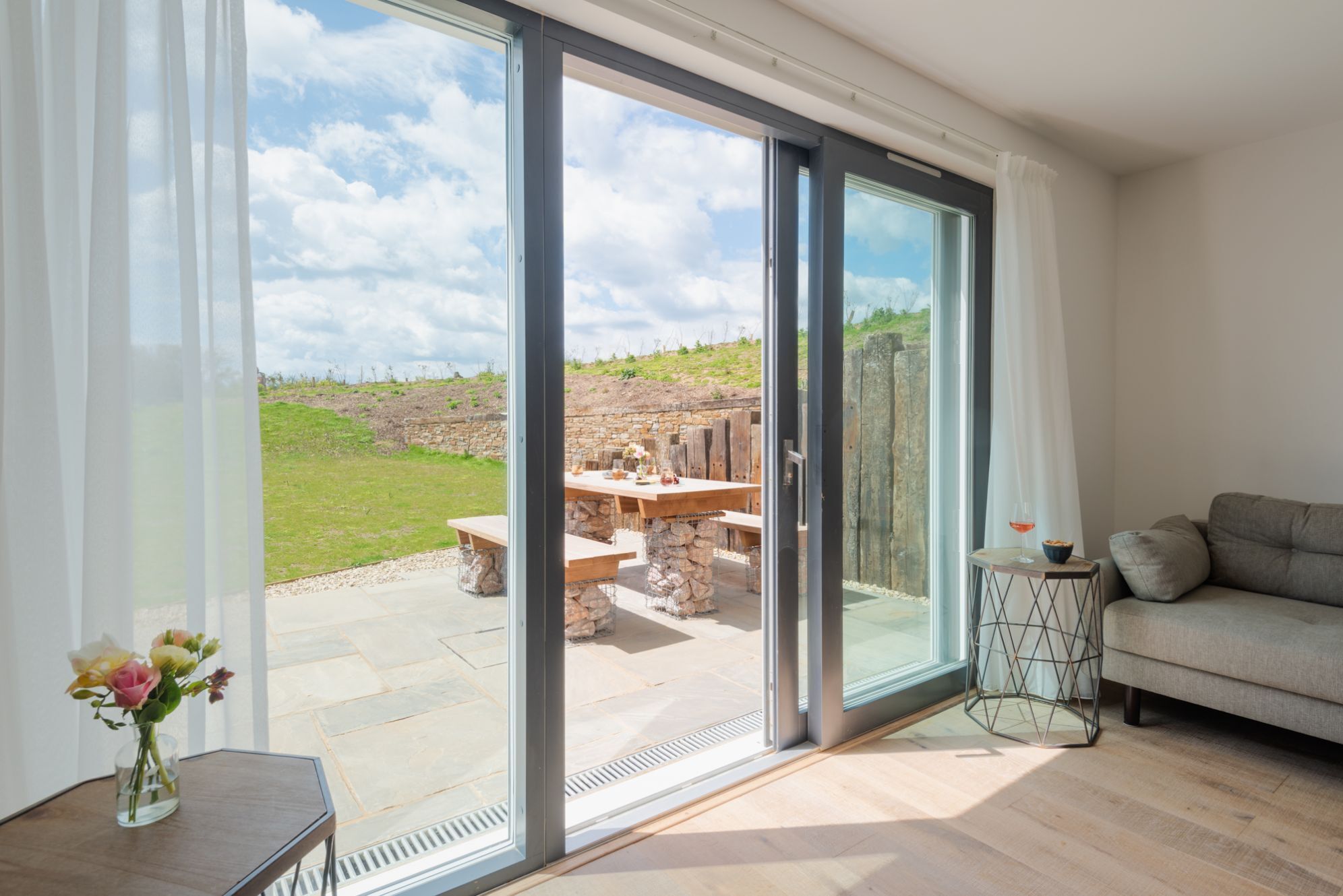 Uma sala de estar moderna com uma ampla porta de vidro deslizante que dá para um espaço de pátio externo.