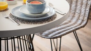 A dining table with a blue bowl of food, a glass of orange juice, and a bowl of berries.
