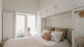 Ein Schlafzimmer mit einem großen Bett, einem Kleiderschrank und einer Glasschiebetür, die zu einem Außenbereich führt.