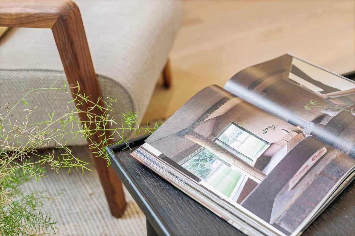 A magazine on a black table with a plant beside it.