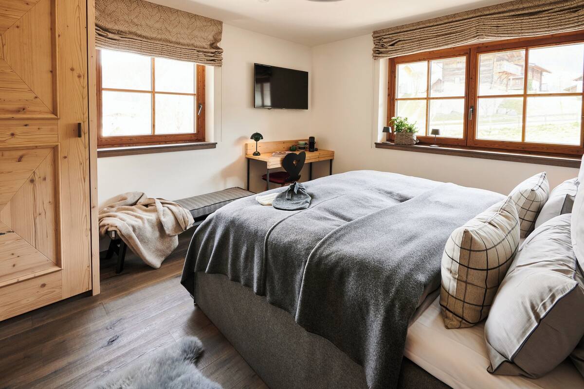 Un dormitorio con cama, escritorio y televisión.