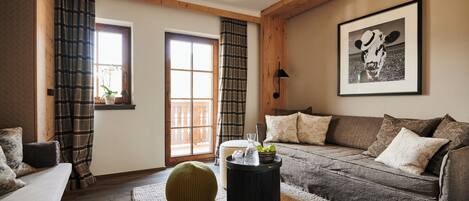 A cozy living room with a sofa, a round ottoman, a coffee table, and a framed picture on the wall.