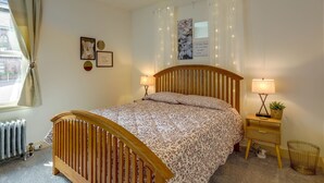 A bedroom with a wooden bed, two bedside lamps, a nightstand with a plant, and a radiator.