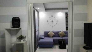 A living room with a sofa, a clock on the wall, a television, and a small table. - Entire New Place For You/todo Nuevo Para Usted (Yumbo)