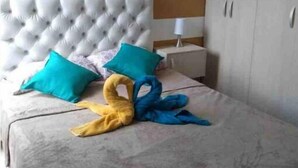 A bedroom with a tufted headboard, striped wall, and a bed with a towel arrangement. - Entire New Place For You/todo Nuevo Para Usted (Yumbo)