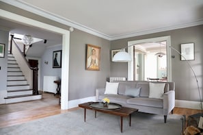 A living room with a grey sofa, a coffee table, and a staircase.